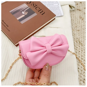 Close-up of pink mini bag with large bow decoration and golden metal chain strap