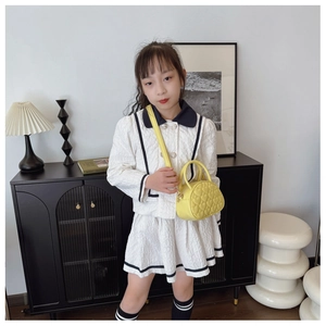 Détail d'un sac à main rond jaune pour enfant avec motifs de couture matelassés en cœur