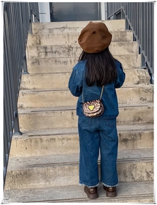Détail d'un mini sac bandoulière léopard avec chaîne sur une tenue enfant en denim