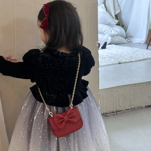 Girl's red crossbody bag with bow and gold chain strap shown on child model