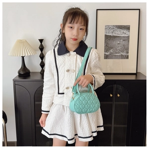 Détail de la texture matelassée en cœur sur un mini sac à main vert menthe pour enfants