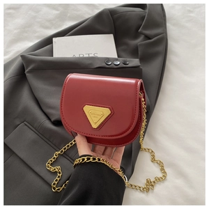 Détail du sac selle rouge avec boucle métallique triangulaire dorée et bandoulière