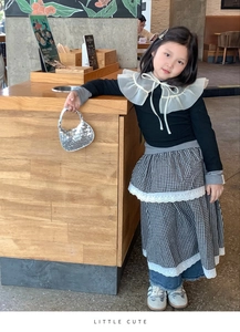 Girl's stylish outfit featuring a sequin crescent handbag and ruffled collar top