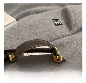 Detailed view of the dark brown lychee leather handle and gold hardware on the bag