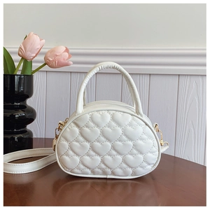 Détail du sac enfant blanc avec matelassage en cœur et mousquetons dorés sur bois