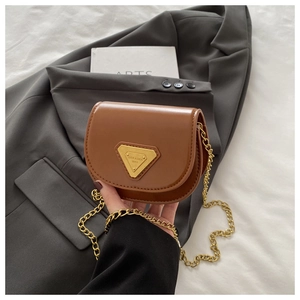 Détail d'un sac bandoulière en cuir marron avec logo triangulaire doré et bandoulière chaîne