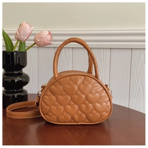 Détails du matelassage en cœur et des ferrures dorées sur un mini sac à main marron