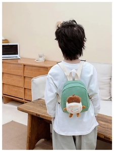 Detail showing the adjustable beige straps and 3D acorn doll on a green canvas backpack