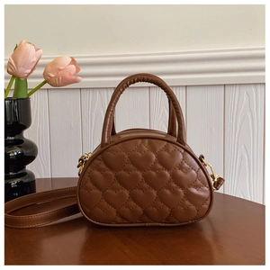 Détail de la texture matelassée en cœur sur un sac à main marron pour fille en similicuir
