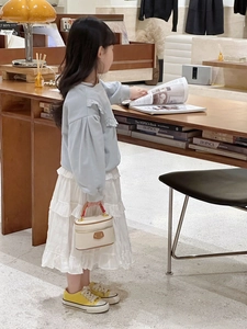 Mini cream-white box bag paired with ruffled blue sweatshirt and tiered white skirt