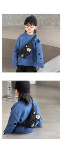 Detailed view of kids black crossbody chest bag with orange tag on blue knit sweater