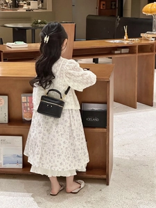Mini black leather box bag with studs worn by a girl in a stylish library setting