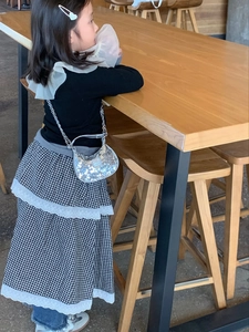 Silver sequin crescent chain bag shown on a girl with checkered lace skirt in a cafe