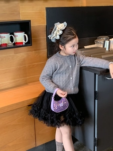 Girl in grey knit cardigan and black tutu skirt holding a purple sequin mini handbag