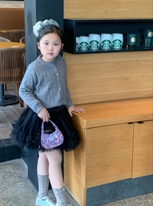 Detail of purple sequin mini handbag paired with grey knit cardigan and tutu skirt
