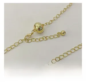 Close-up of golden metal chain strap with adjustable quilted ball and lobster clasp