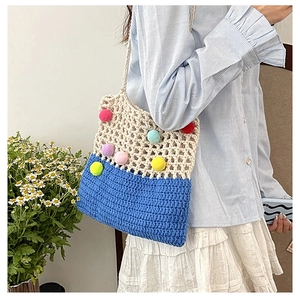 Close-up of handmade crochet shoulder bag with colorful pom-poms and mesh texture