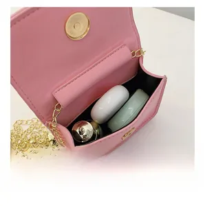 Pink mini crossbody bag interior showing storage for earphones and lipstick with chain