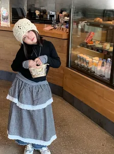 Fillette en tenue vintage avec chapeau crocheté et jupe à carreaux vichy à volants noirs