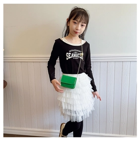 On-body shot of a mini bright green crossbody bag for kids with a gold chain strap