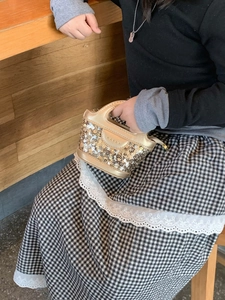 Gros plan d'un enfant portant un sac à main à paillettes dorées avec une poignée pratique