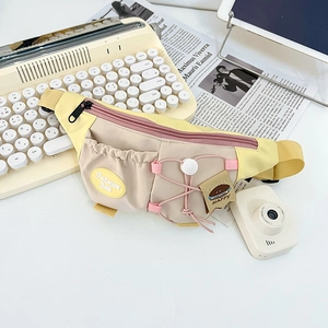 Close-up of cream crossbody chest bag featuring fashion logo and biscuit charm detail