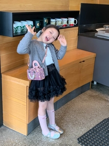 Pink sequin mini crossbody bag with pearl handle on a young girl in a stylish outfit