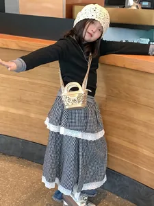 Fillette à la mode portant un mini sac à paillettes dorées avec jupe à carreaux et chapeau
