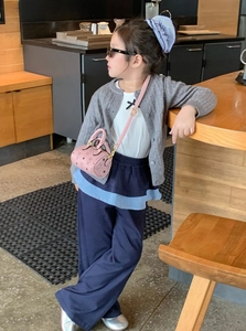 Detail shot of a stylish girl wearing a pink mini cylinder bag and knit cardigan outfit
