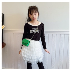 Close-up of a girl's black printed tee with white layered lace cake skirt and green bag