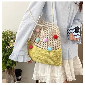 Detail of crochet shoulder bag with colorful pom-poms and cream hollow-out knit pattern