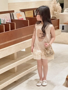 Detail of a beige sleeveless dress with heart print and a gold sequin kids handbag