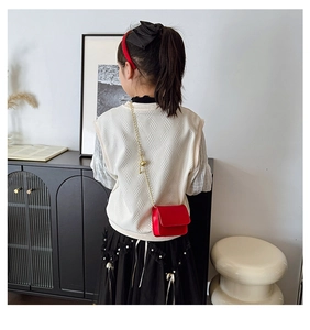 Rear view of child wearing a red leather mini crossbody bag with a gold chain strap