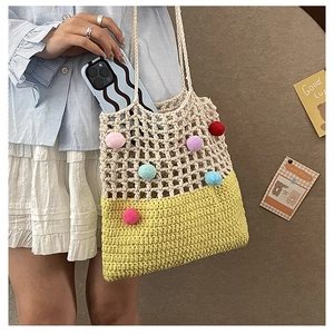 Detail of crochet shoulder bag with colorful pompoms and hollow mesh pattern showing its size