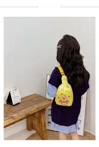 Rear view of a girl wearing the yellow Capybara cartoon crossbody bag on a wooden bench