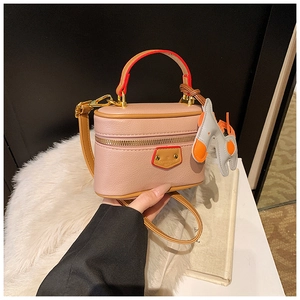 Detailed view of pink pebble leather mini box bag with orange handles and horse charm