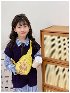 Kid wearing yellow Capybara sling bag with donut print and adjustable strap in cozy setting