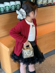 Detailed view of kids red knitted cardigan with golden sequined pearl handle handbag