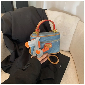 Detail of blue denim mini handbag with brown leather handle and cute pony charm