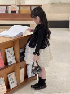 Detail of girl wearing black sequin vest with white floral petal skirt and sequin handbag