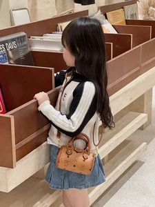 Girl carrying a bear print brown Boston mini bag in a library setting with gold hardware