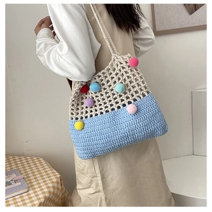 Detail of crochet tote bag featuring colorful pom-poms and a blue knitted lower section