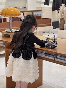 Detail of girls' sequin handbag with large bow back dress in a cozy interior setting