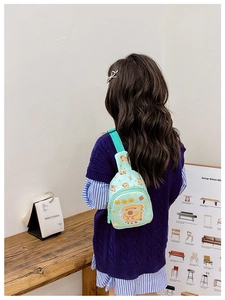 Detail of mint green kids crossbody bag featuring a cute cartoon toast bear print design