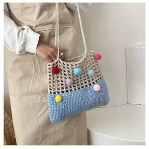 Detail of crochet tote bag featuring multi-color pom-poms and blue knit contrast