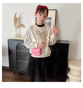 Close-up of pink mini crossbody bag paired with sequin bow sweatshirt and lace tutu skirt
