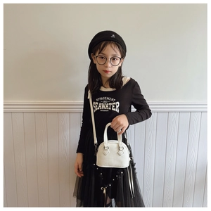 Close-up of white lychee pattern mini shell bag with dual handles on child model