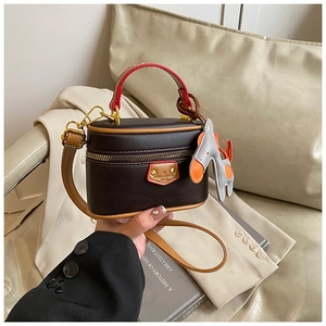 Detail of lychee textured leather mini box bag with horse charm and brown strap