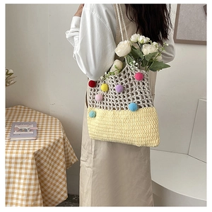 Detail of hand-woven shoulder bag with colorful pom-poms and hollow mesh knit design