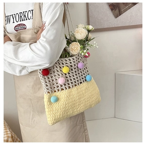 Detail of crochet tote bag featuring multi-colored pom-poms and mixed knit textures